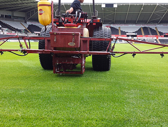 A tractor and sprayer being used to apply Maxstim biostimulants to the turf at Liberty stadium in Swansea, Wales