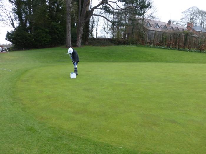 A groundskeeper applying Maxstim biostimulants to a green at Dunmurry Golf Club. The turf appears healthy and green as a result of the treatment.
